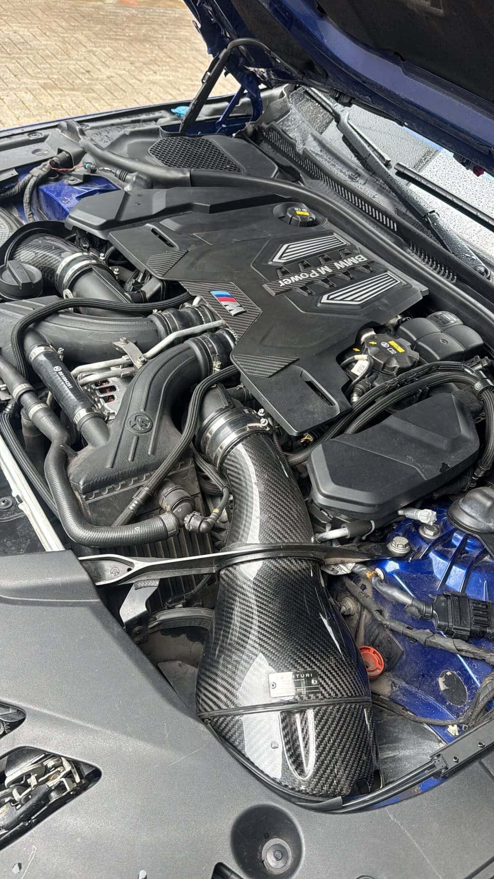 Geopende motorruimte met een M-motor en carbon luchtinlaat